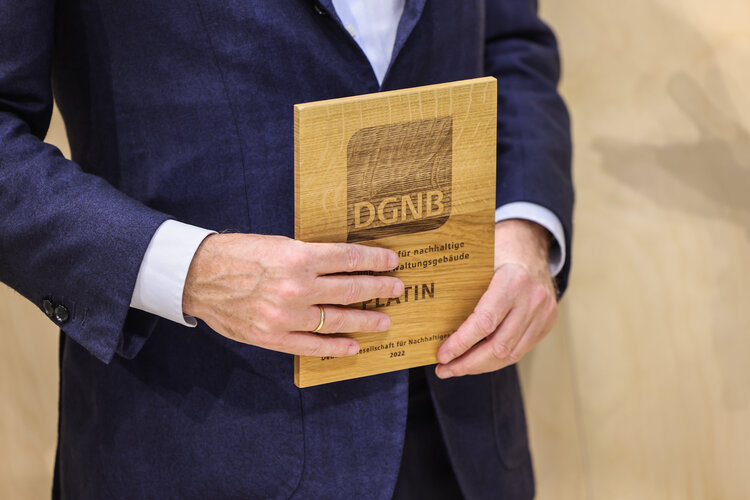 Plakette für DGNB-Zertifikat in Platin von einem Mann im Anzug aufgenommen